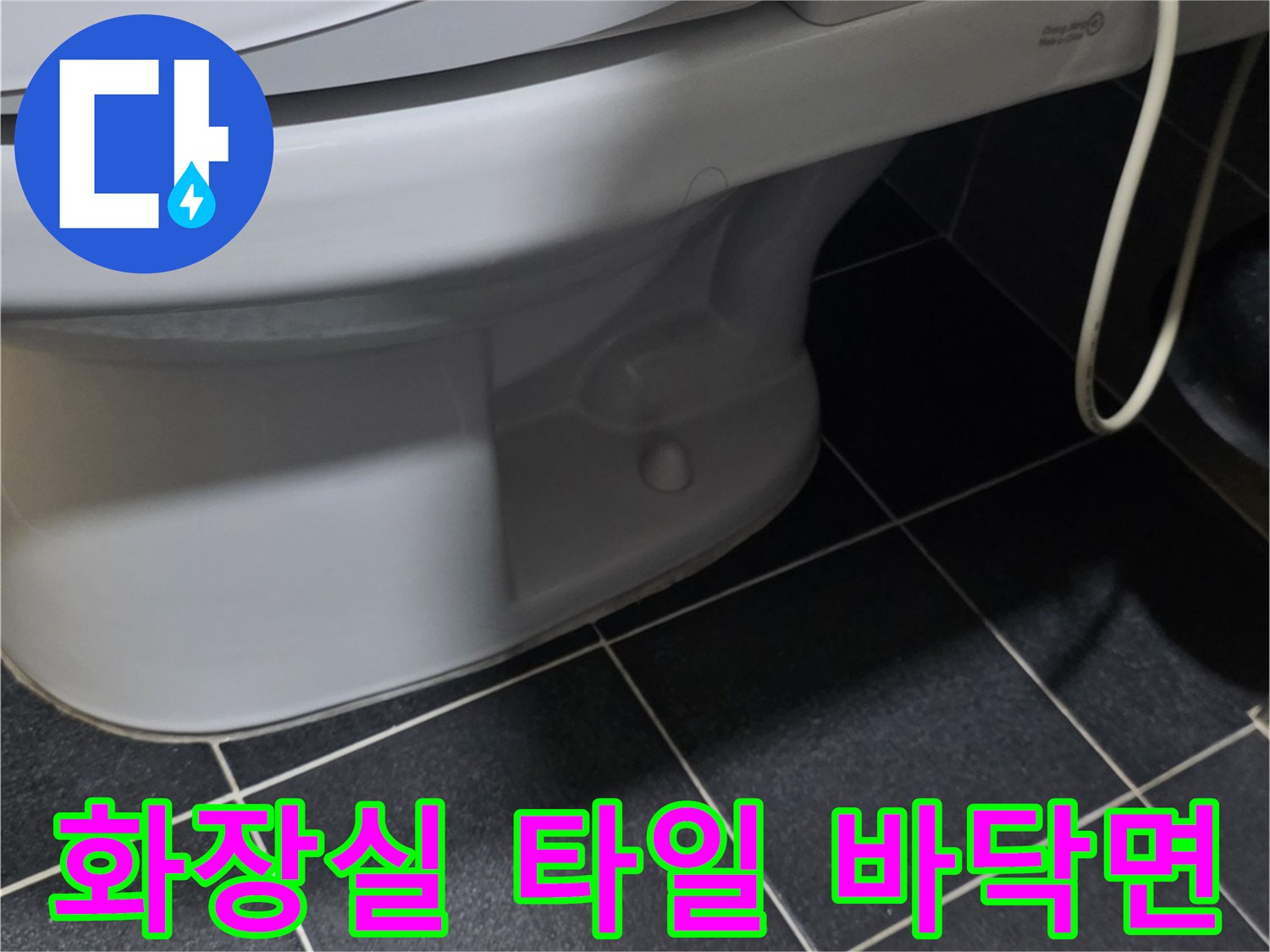 어두운 색상의 화장실 타일과 변기 하단부 모습입니다.