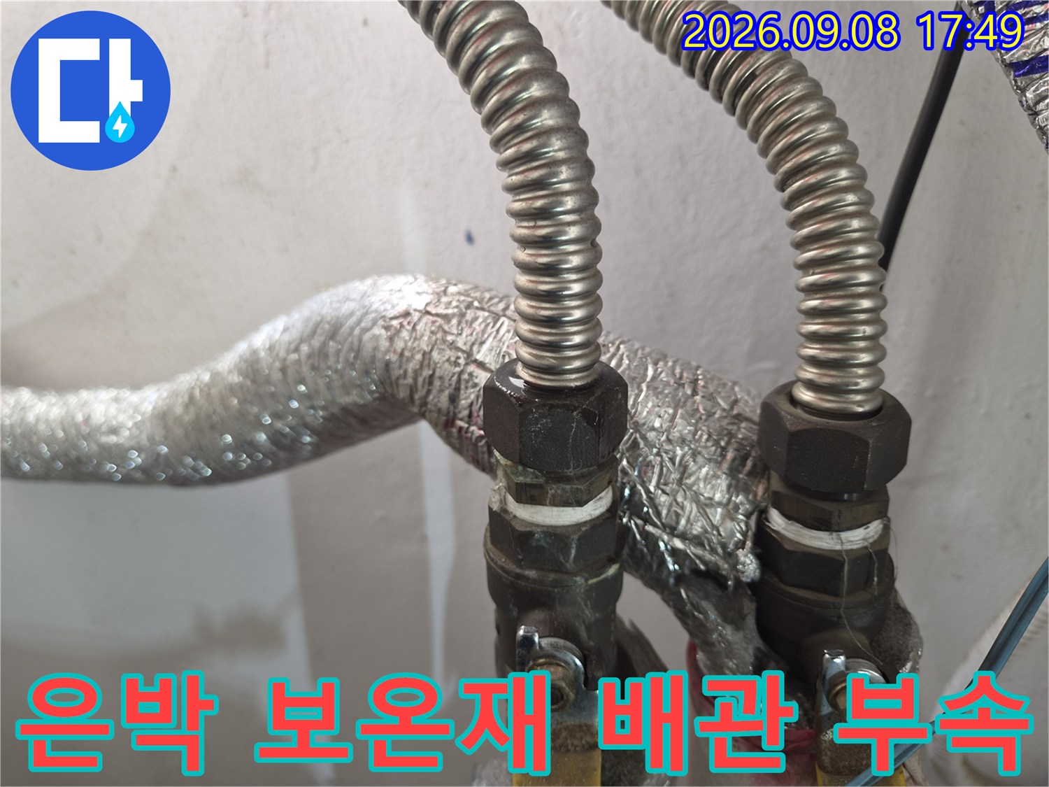 금속제 연결 부품과 은박 보온재가 씌워진 배관의 모습