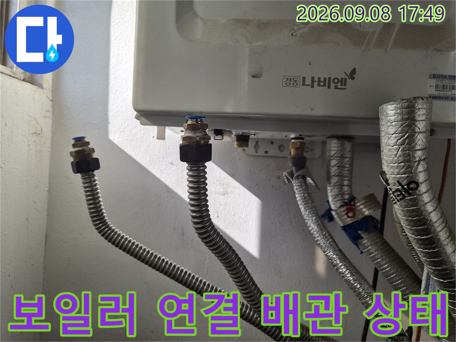 보일러 하단에 연결된 은색 보온재 배관과 금속 연결 부위 상세 사진