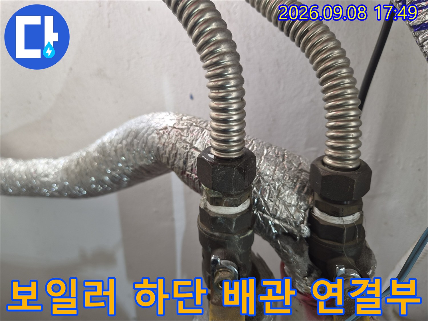 은박 보온재가 씌워진 금속제 배관 연결 부위의 근접 촬영