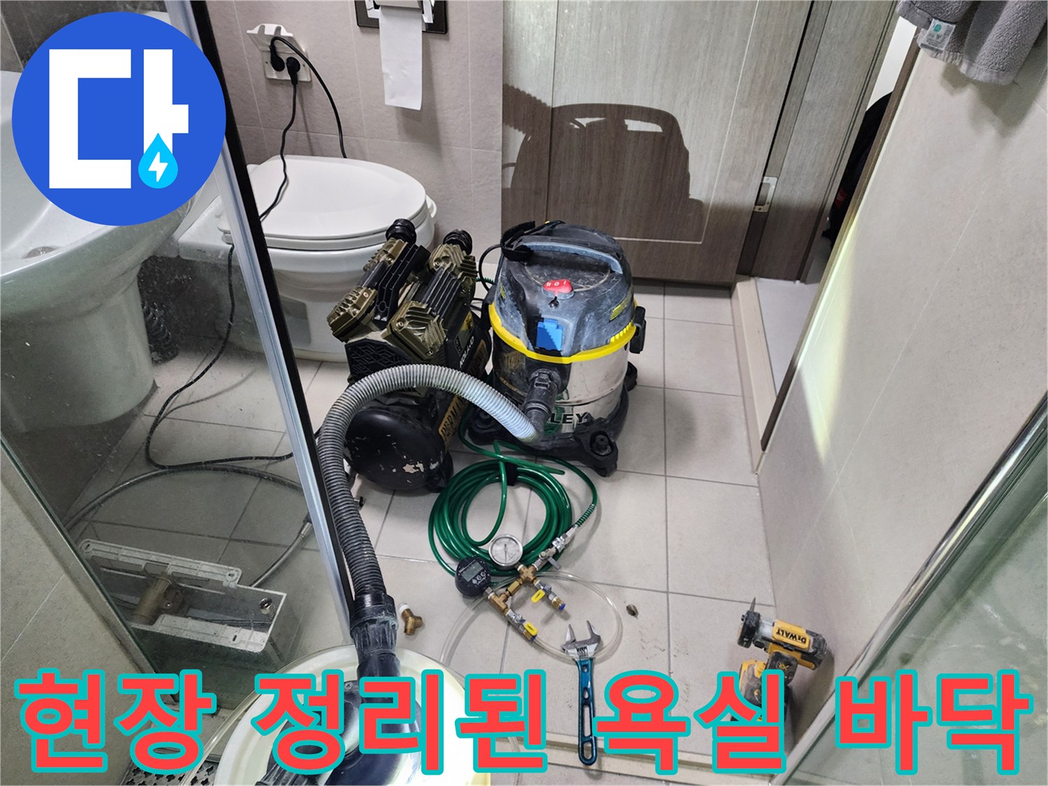 청소기와 배관 점검 도구가 놓인 화장실 내부