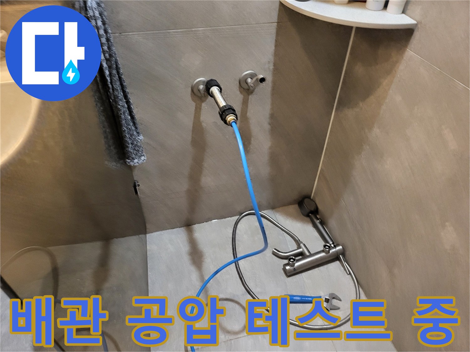 벽면 배관에 연결된 파란색 압력 측정 호스