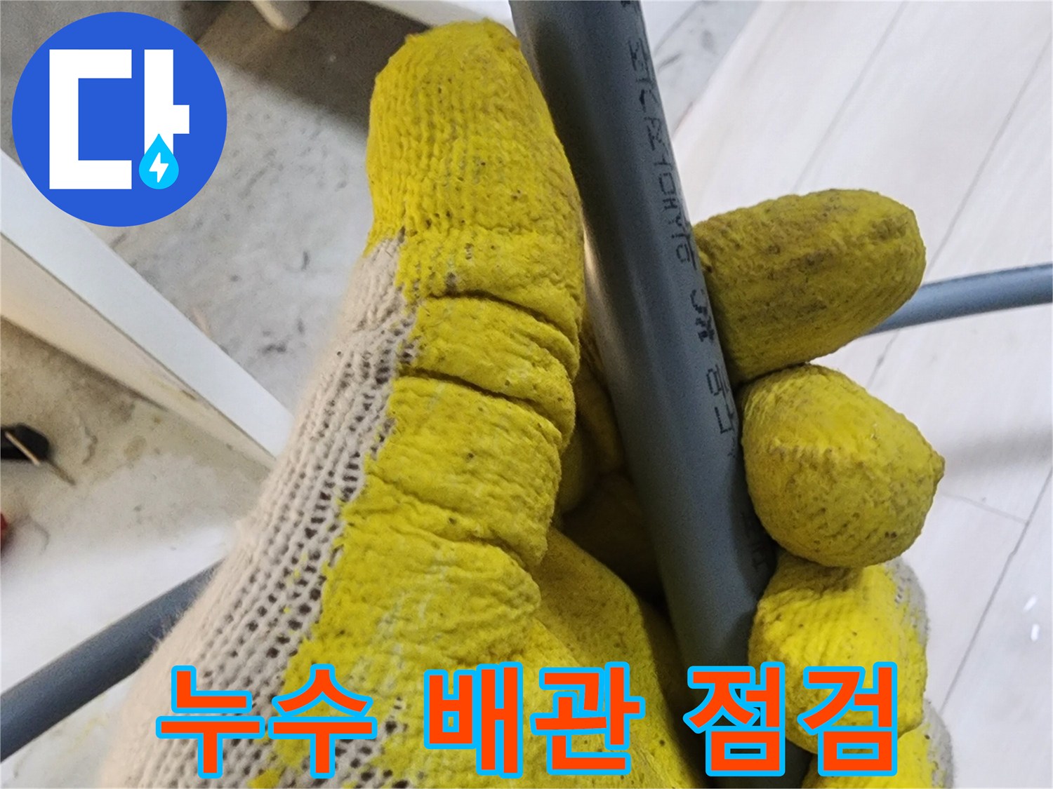 작업용 장갑을 낀 손이 회색 관을 잡고 있는 모습