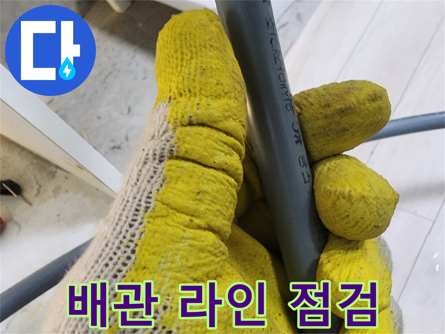 작업자가 회색 수도관을 잡고 상태를 살피는 장면