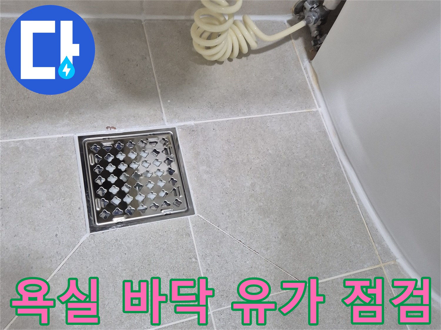 타일로 마감된 욕실 바닥의 스테인리스 배수구 덮개 사진입니다.