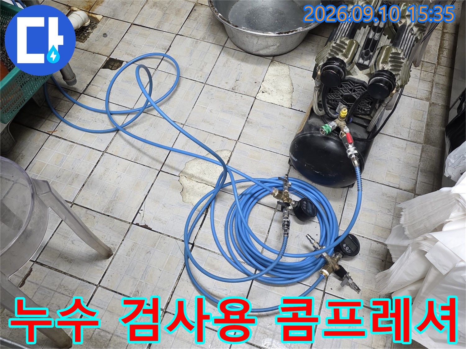 타일 바닥 위로 펼쳐진 파란색 호스와 공압 테스트 장비 모습