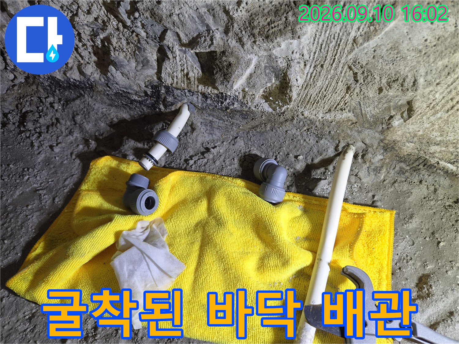 삼가동 공사 현장-굴착된 바닥면 위에 배치된 배관 자재와 측정 도구