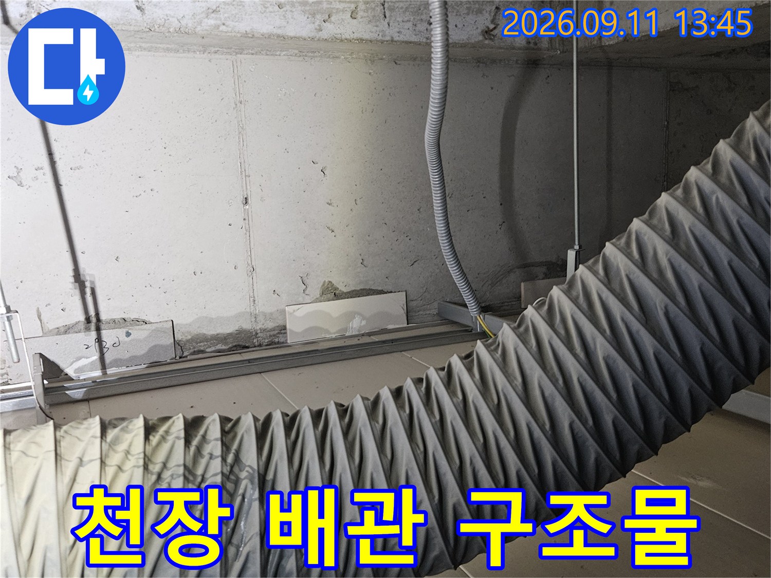 천장 내부의 굵은 주름 배관과 전기 배선 노출 상태