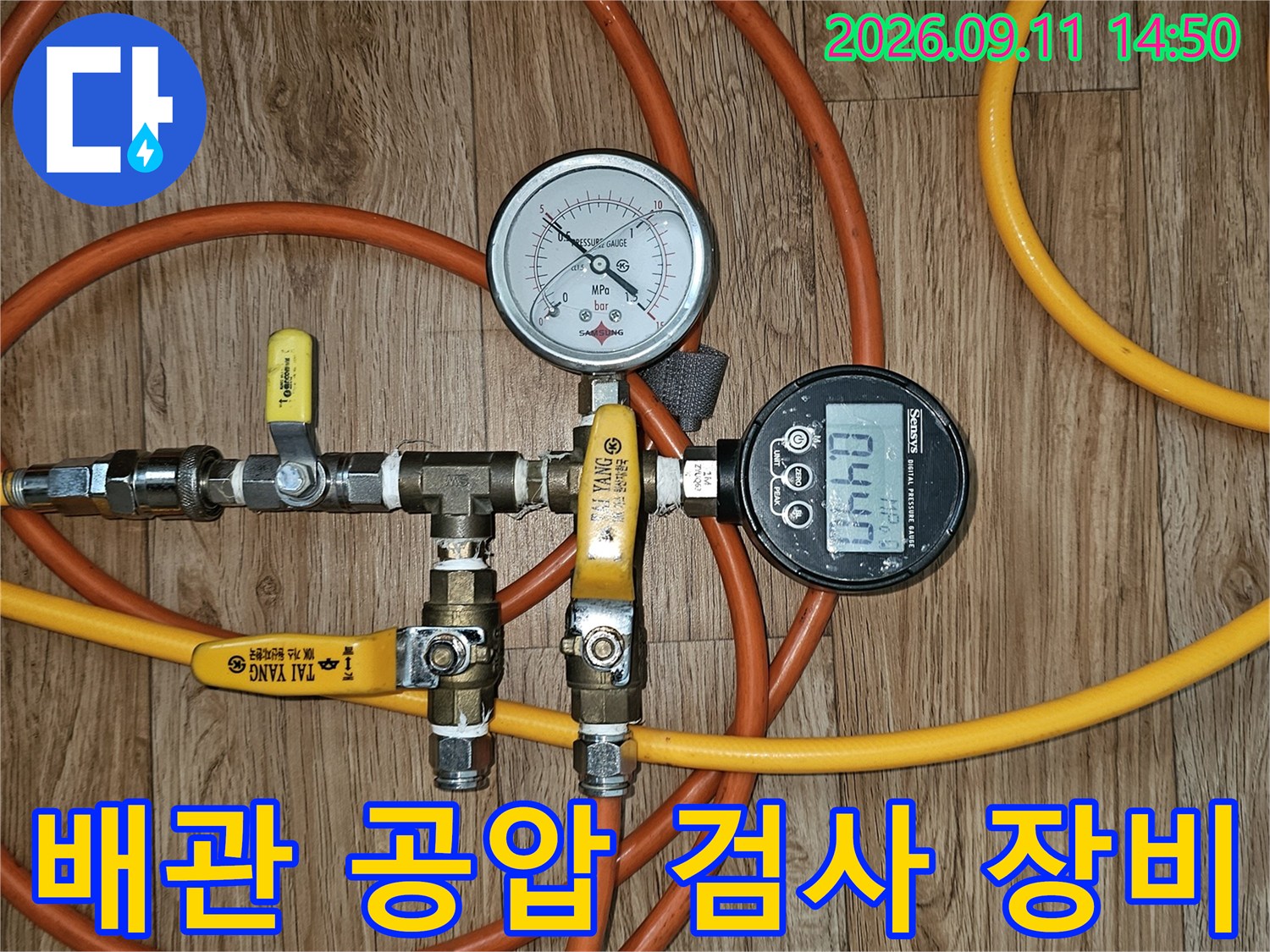 노란색 호스와 압력 게이지가 연결된 배관 점검 장치 세부 모습
