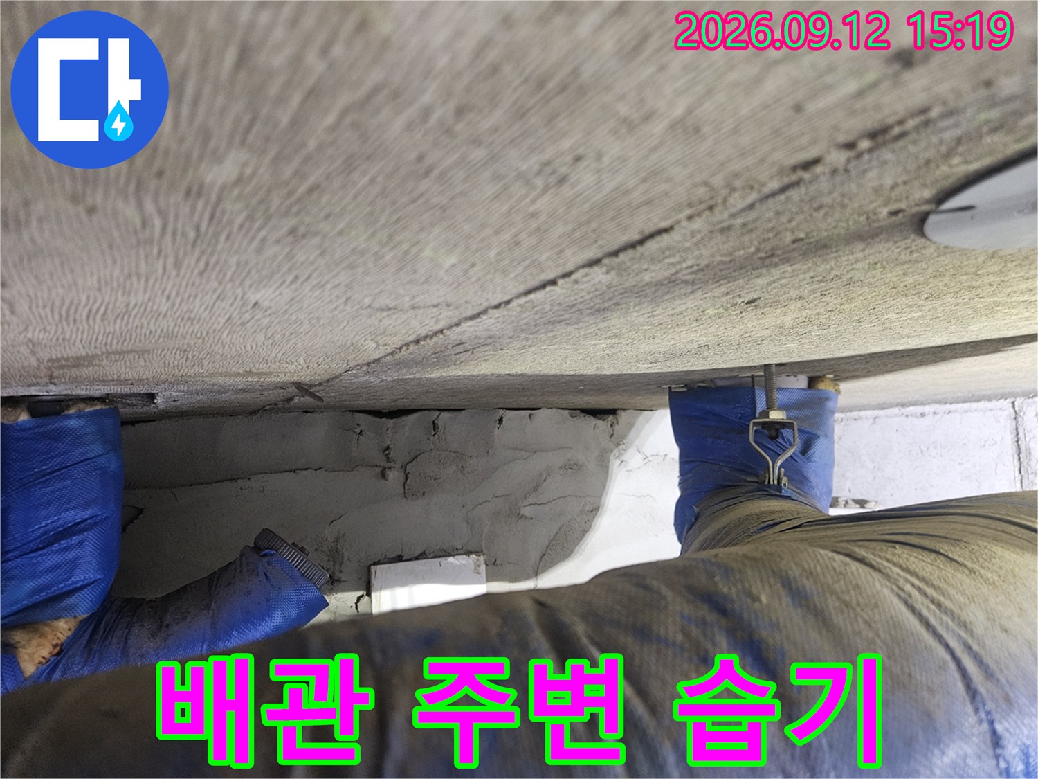 물기가 스며든 콘크리트 슬라브와 파란색 테이프 배관