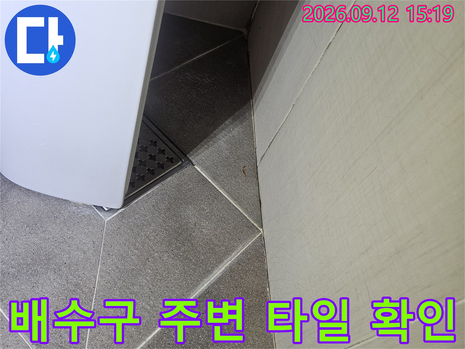 세면대 하부 배수구와 회색 벽면 타일 상세 이미지