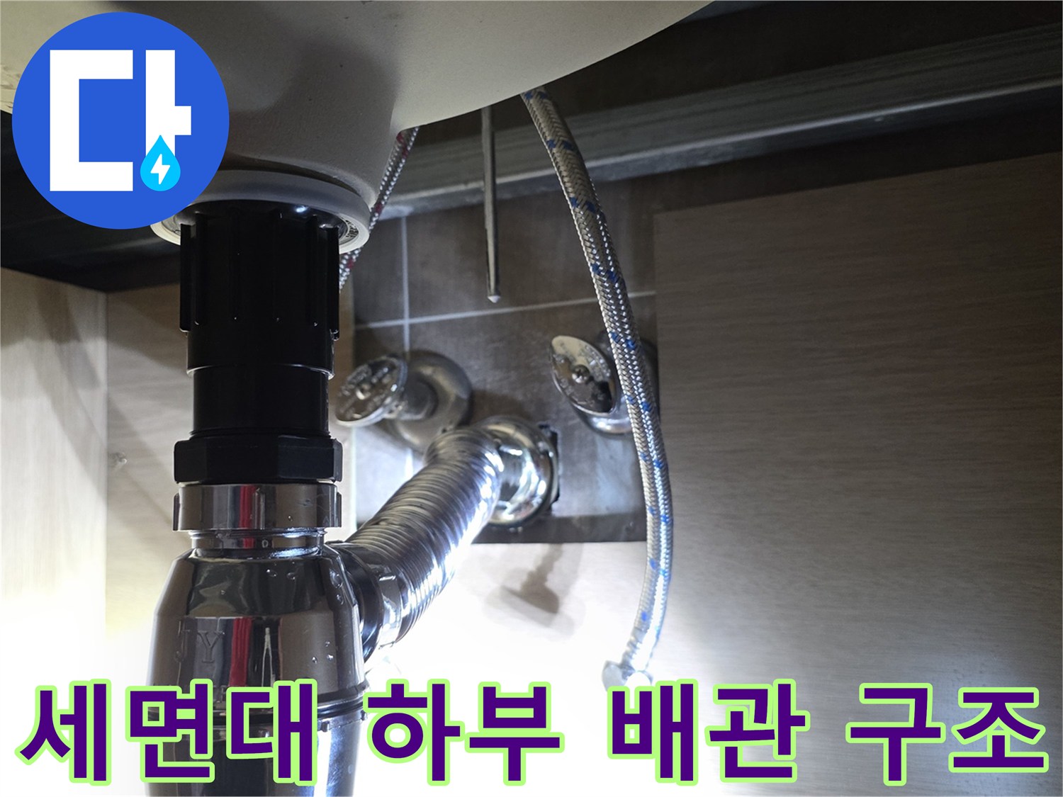 은색 주름 호스와 트랩이 연결된 세면대 하부 구조