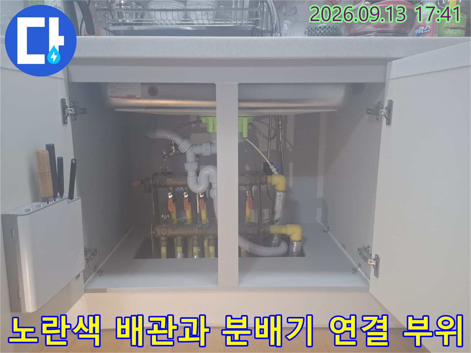 싱크대 아래 보일러 분배기와 노란색 PE-RT 배관이 연결된 상세 모습입니다.