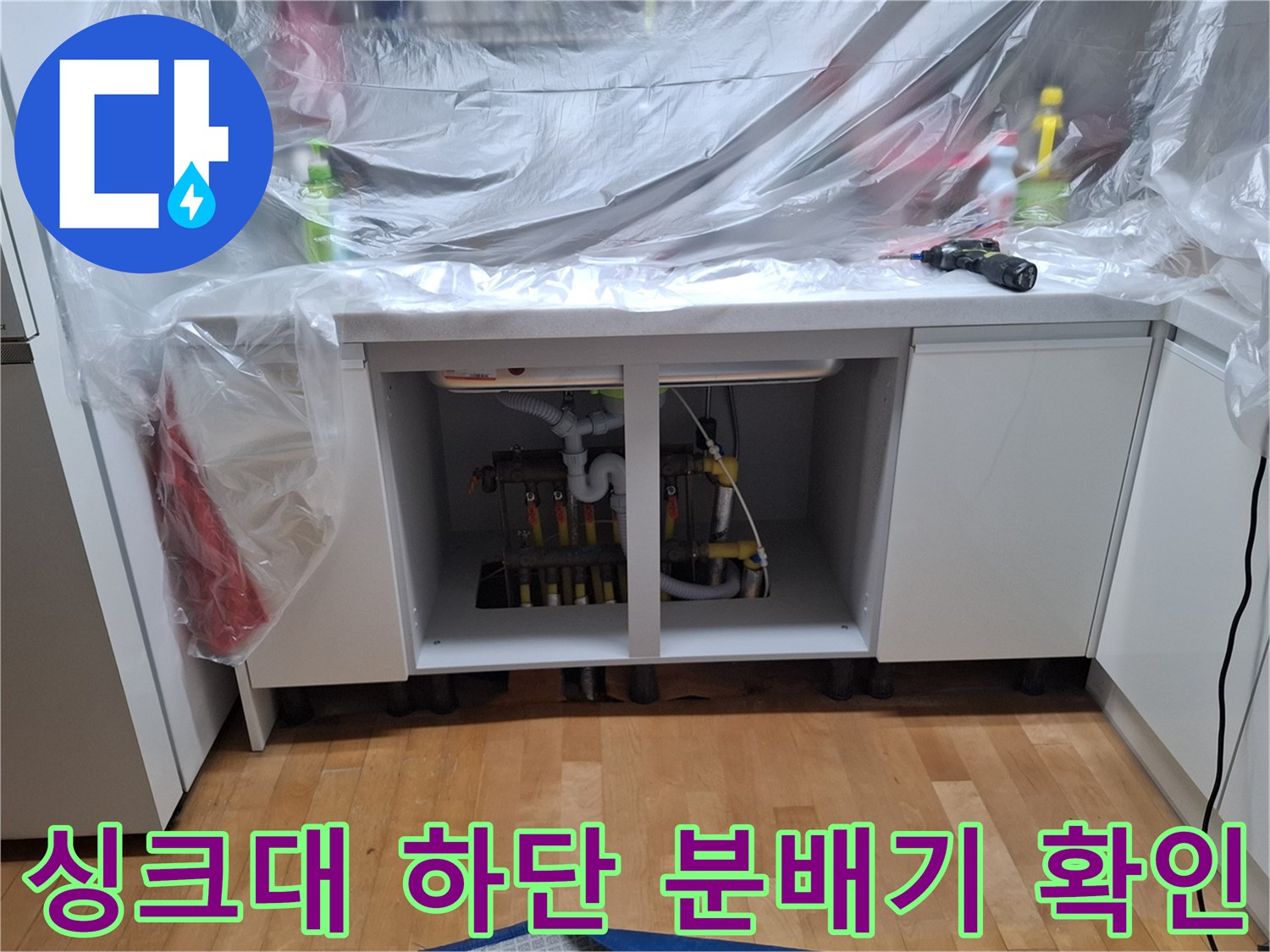 싱크대 하부장 내부의 난방 분배기와 배관 점검 상태