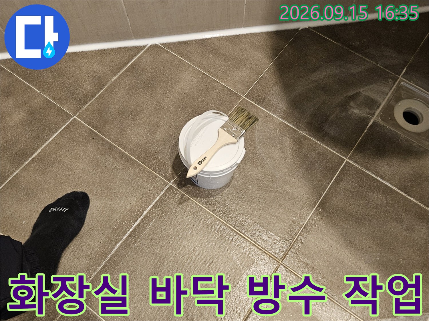 화장실 타일 바닥에 놓인 방수제와 붓