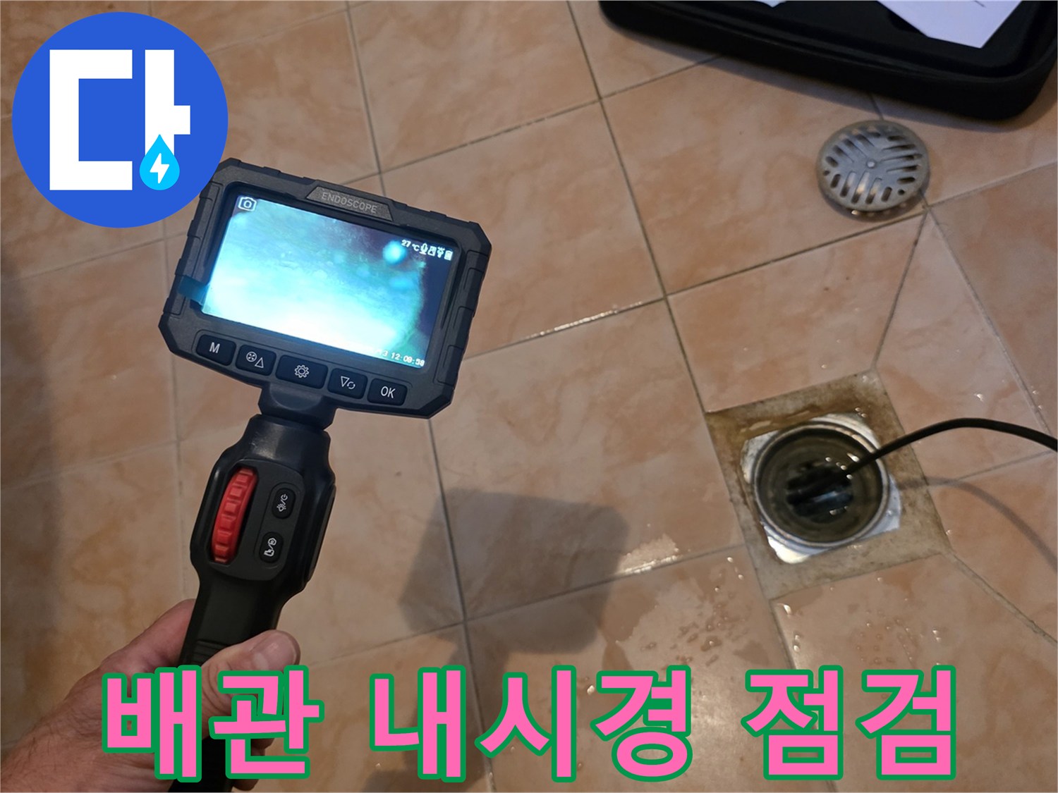 화장실 바닥 배관 내부를 확인하기 위해 내시경 카메라를 투입하는 모습입니다.