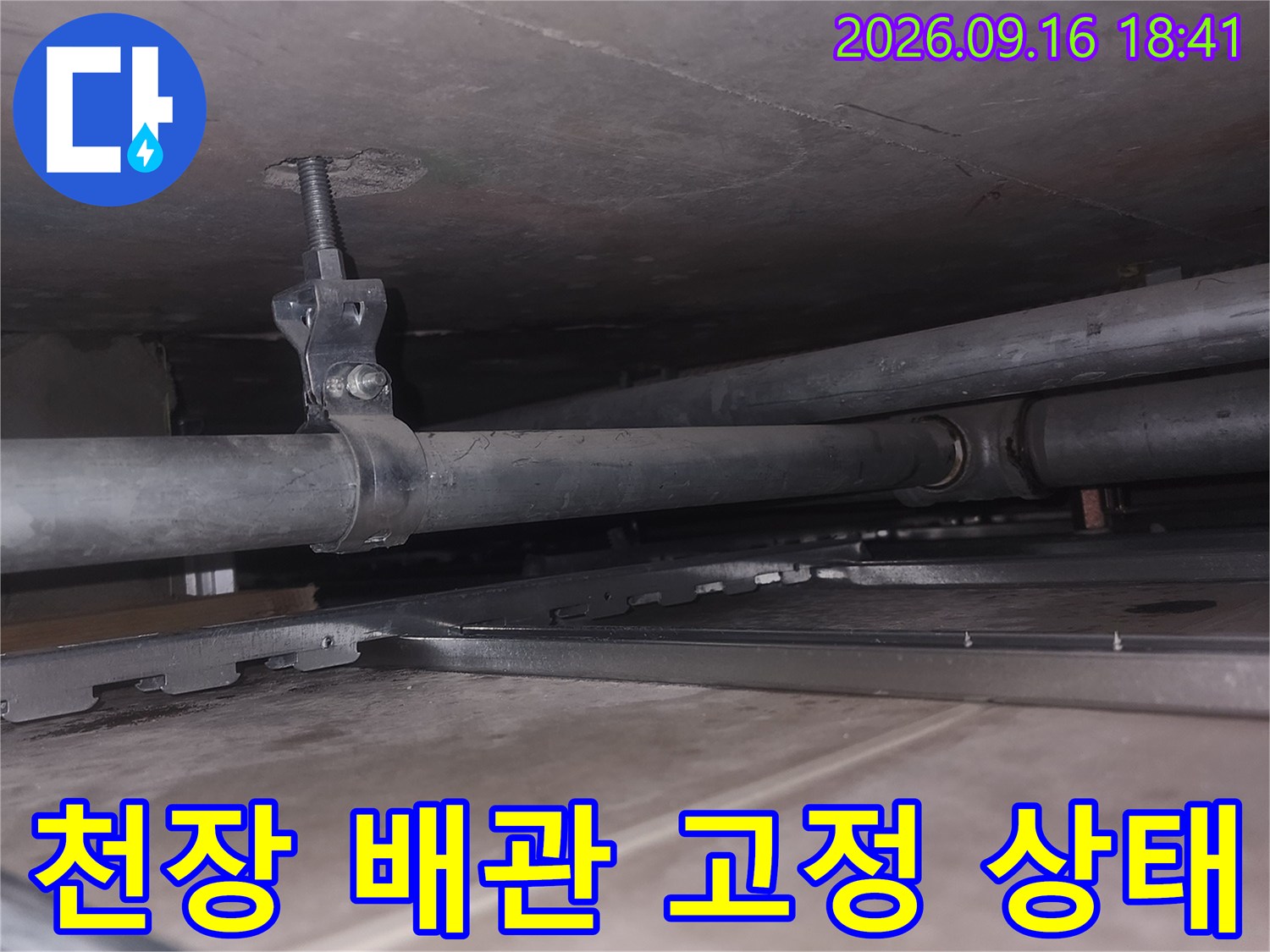 천장 구조물에 설치된 수직 배관과 클램프