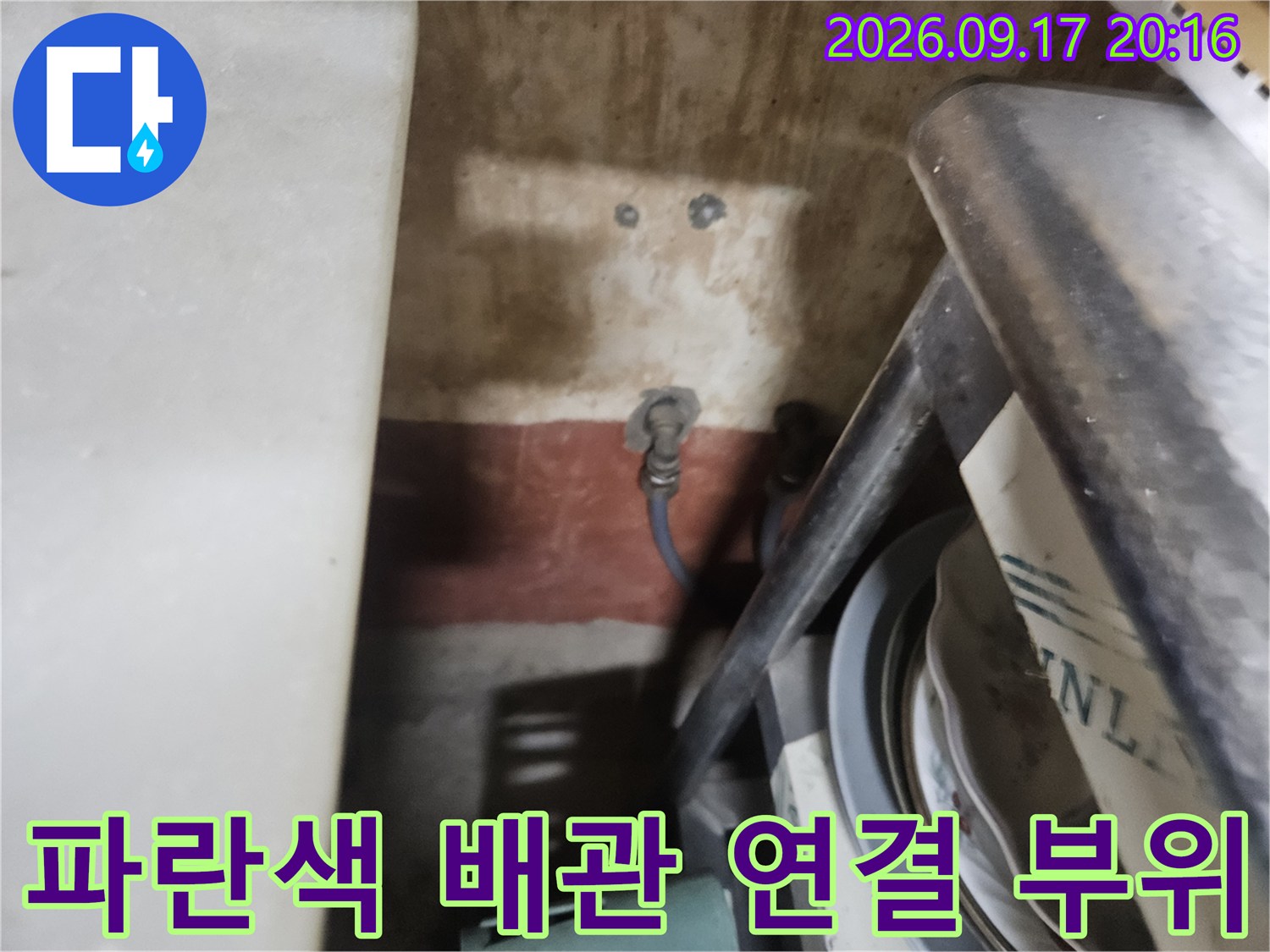 바닥에 노출된 파란색 온수 배관과 보일러 연결 부속의 상세 모습입니다.