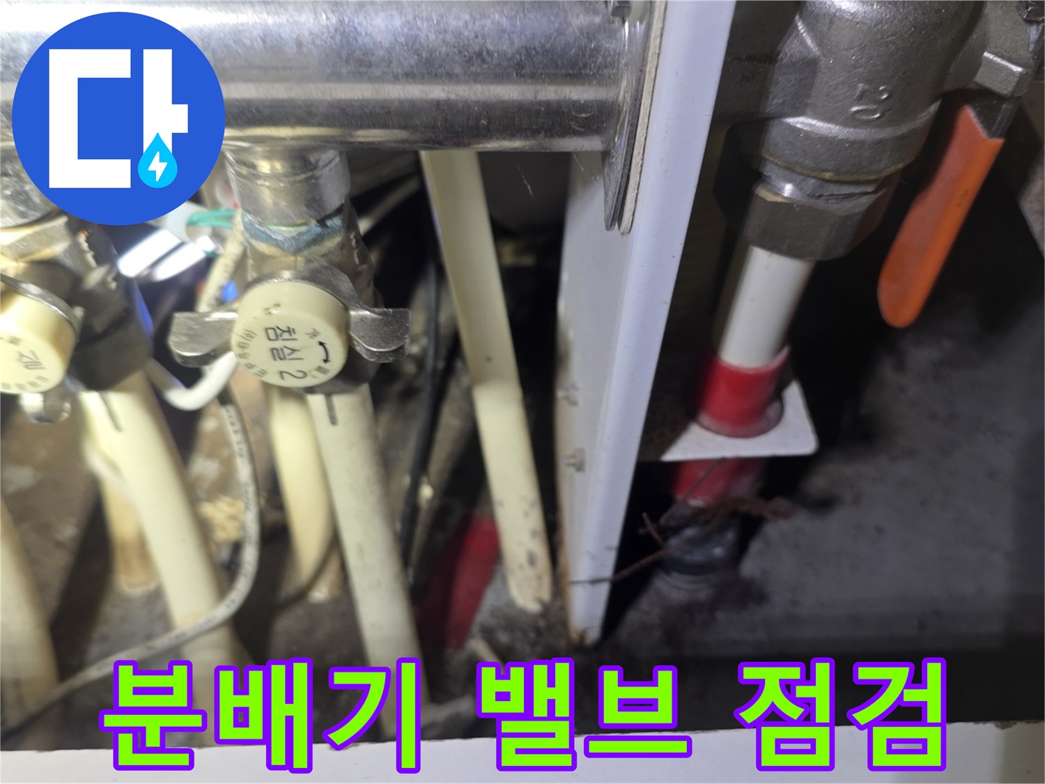 보일러실 내 설치된 분배기의 금속 밸브와 흰색 배관 연결 부위 모습입니다.